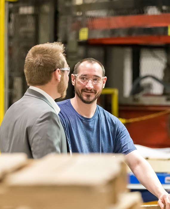 Two guys in safety glasses discussing a project